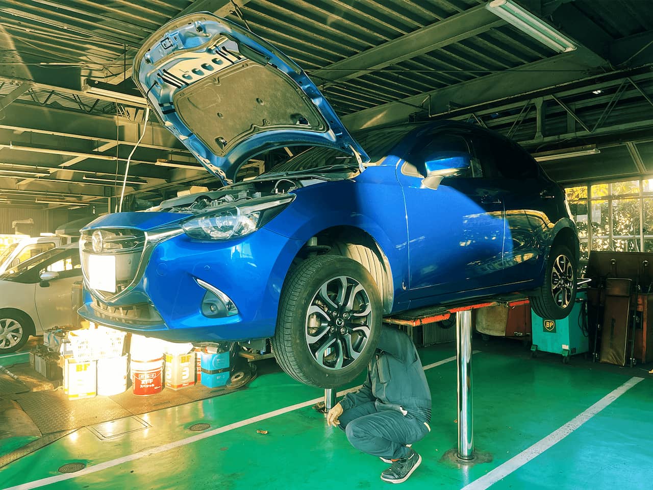 リフトアップしている車の下で作業をする整備士